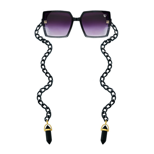 Square sunglasses with dark purple gradient lenses attached to a black chain featuring gold detailing-front view