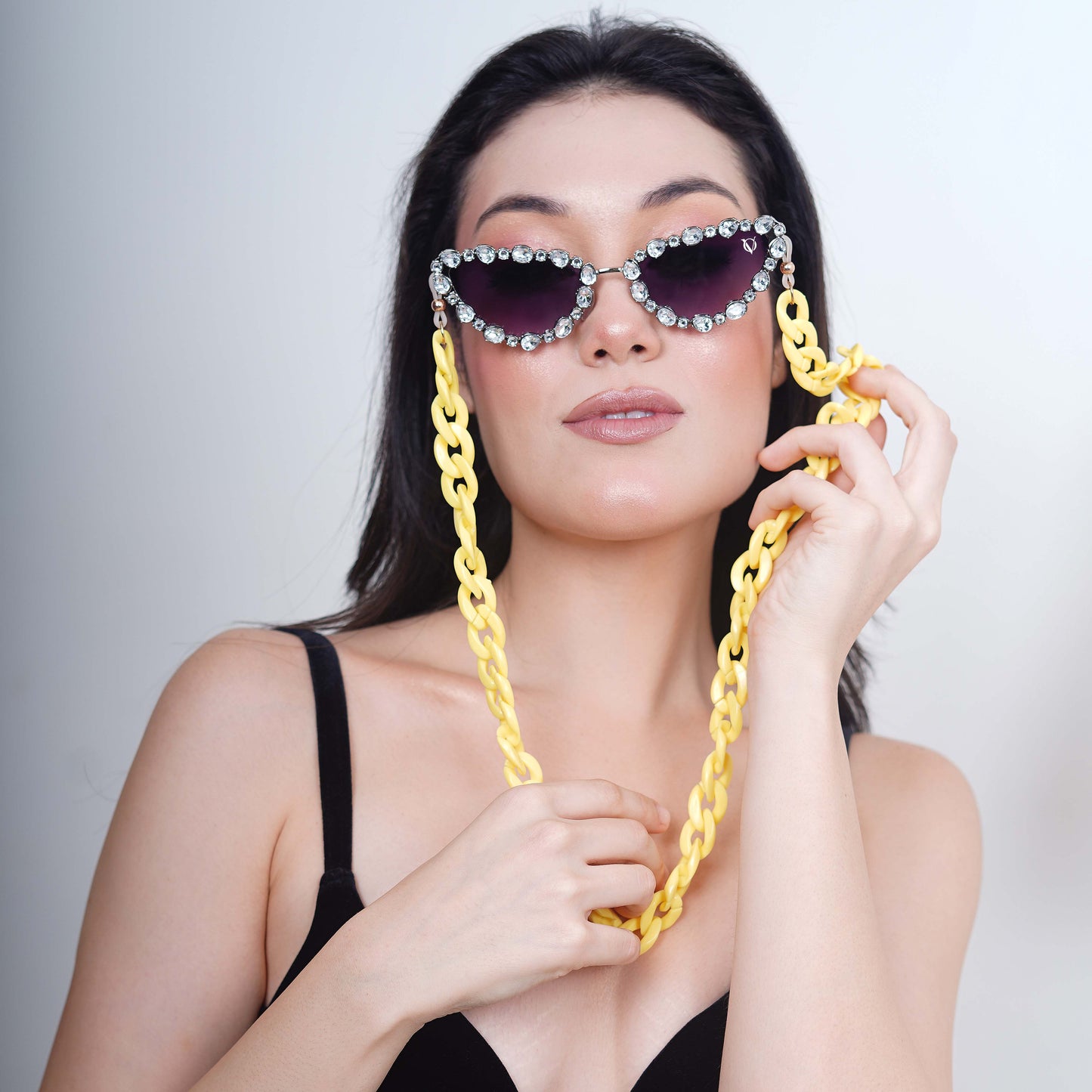 Glimmery oval crystal-studded cat-eye frames with blue gradient lenses attached with a yellow funky chain for trend lovers-styling pose