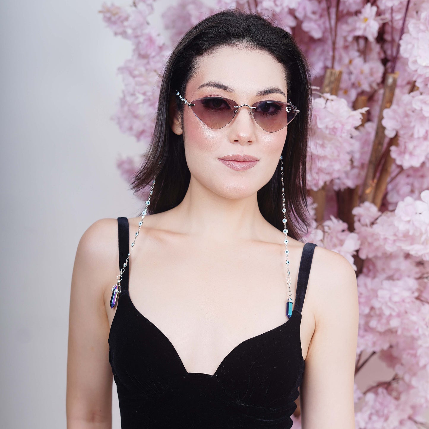 Luxury cat-eye frames with brown-gold tinted lenses adorned with silver-toned evil eye chain and multicolored vibrant charms-side angle pose