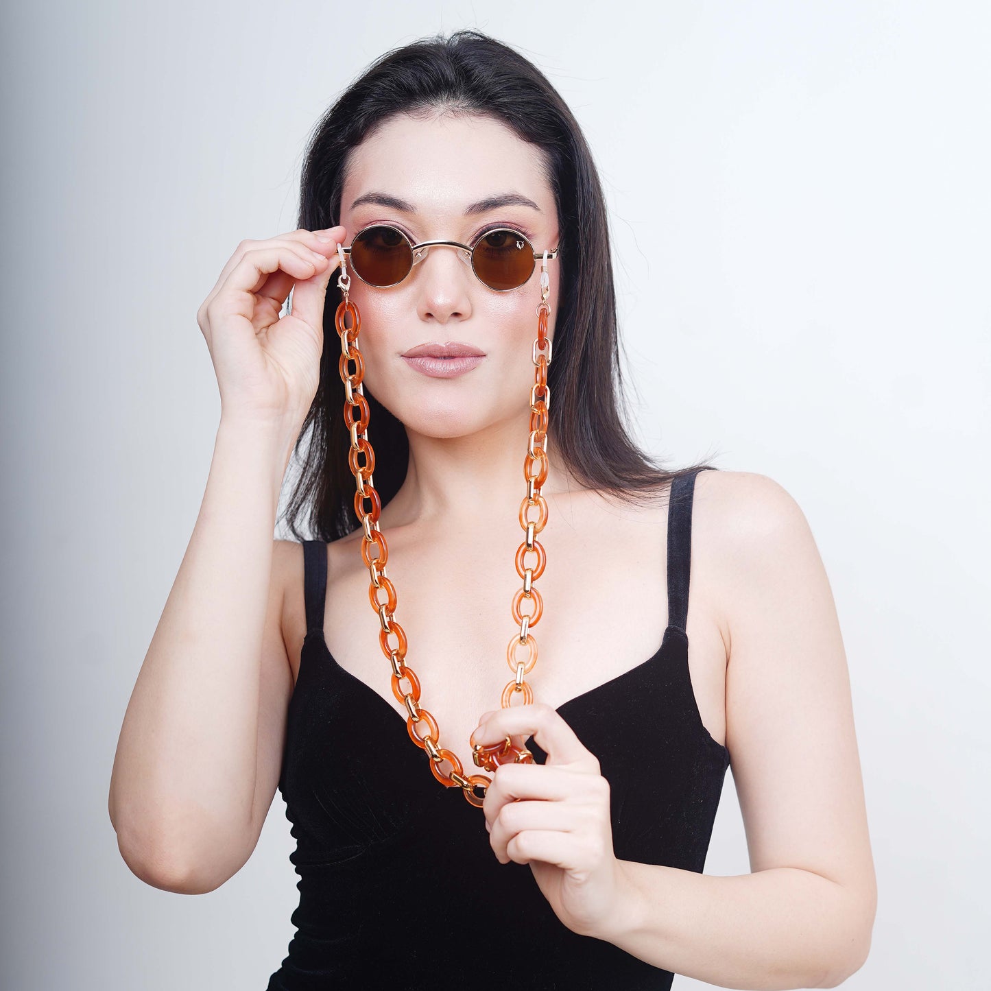 Luxurious brown tinted round oval lenses attached with a large funky orange chain linked with a gold linker.