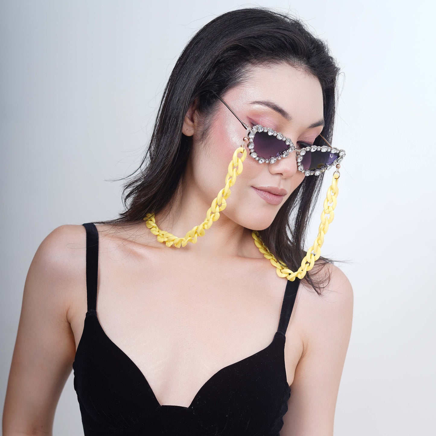 Glimmery oval crystal-studded cat-eye frames with blue gradient lenses attached with a yellow funky chain for trend lovers-angle pose