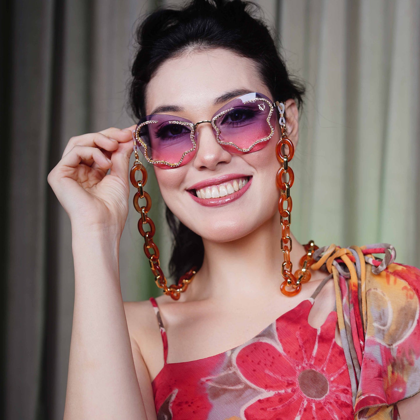 Shimmery red-purple gradient lens with gold glittery boundary attached with orange oval rings chain with gold linker-smile view