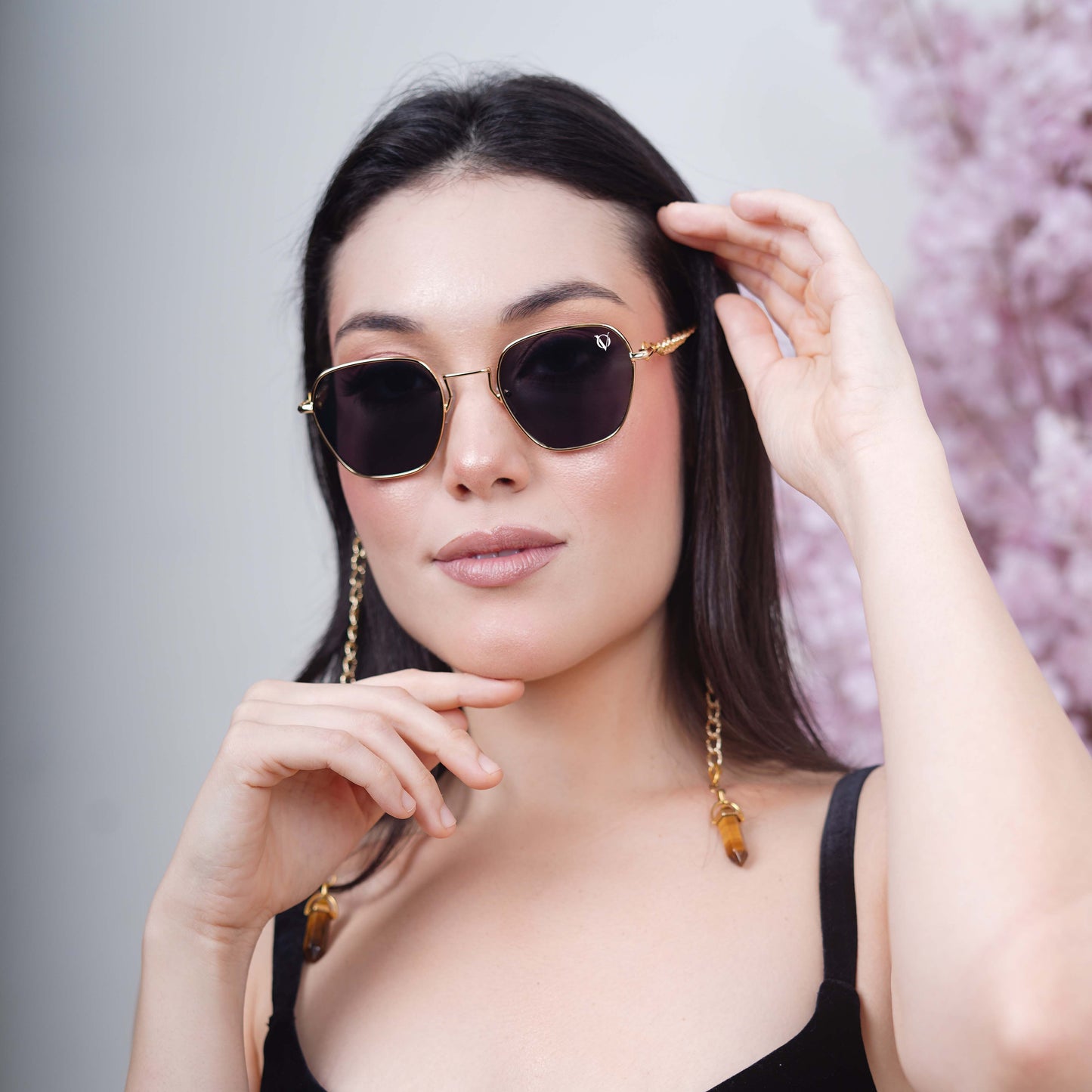 Black tinted large lenses with gold finishing attached with a golden chain with golden clear lenses finished with a gold metal holder-styling pose