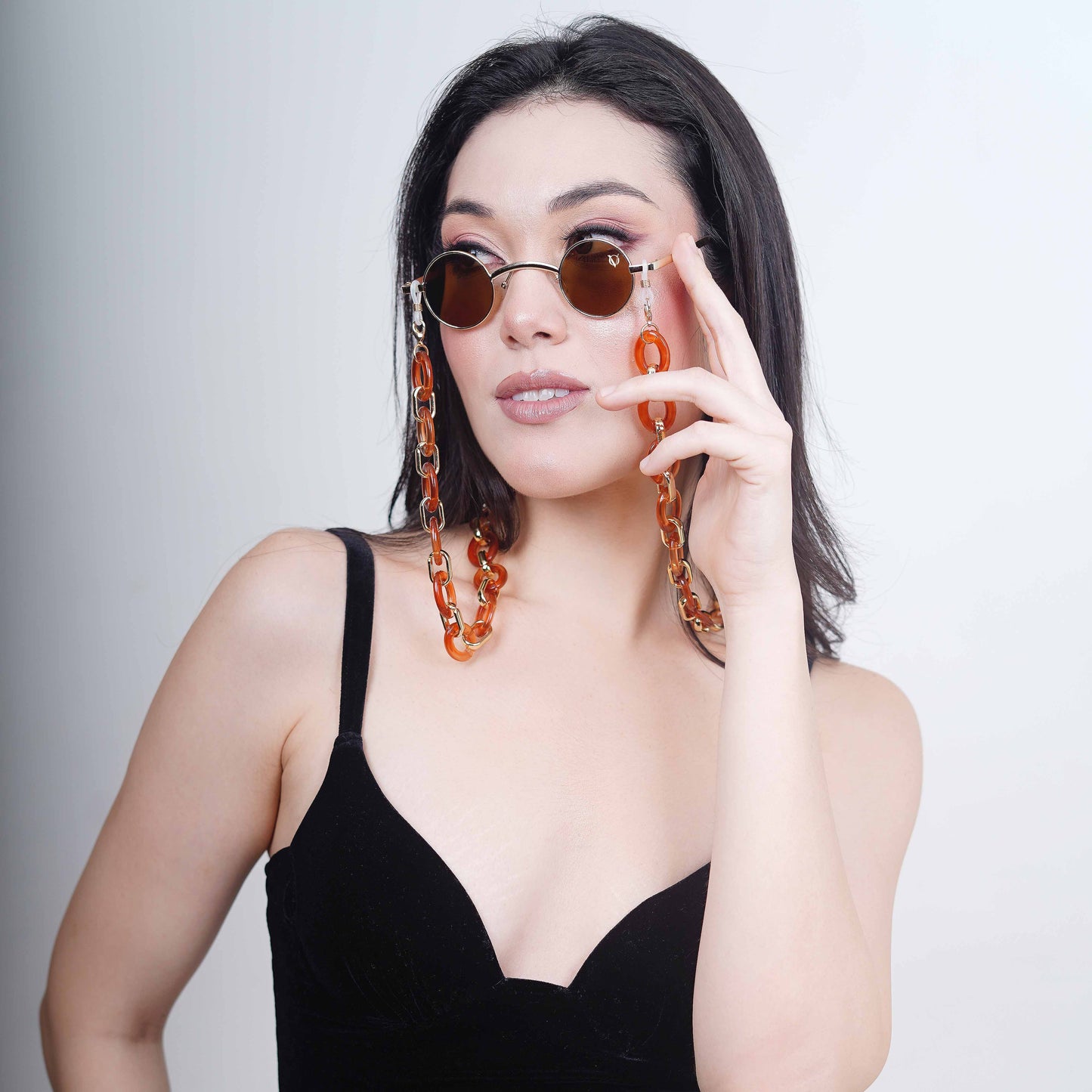 Luxurious brown tinted round oval lenses attached with a large funky orange chain linked with a gold linker-angle pose
