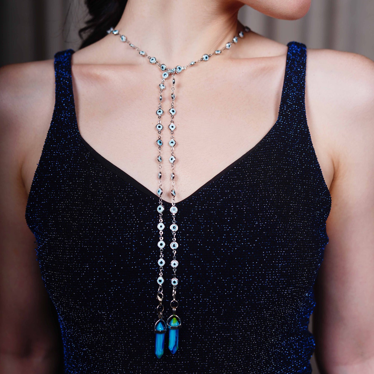 Round black lenses with gold frame attached to evil-eye beaded silver chain attached to blue stone charm with a silver cap-charm view