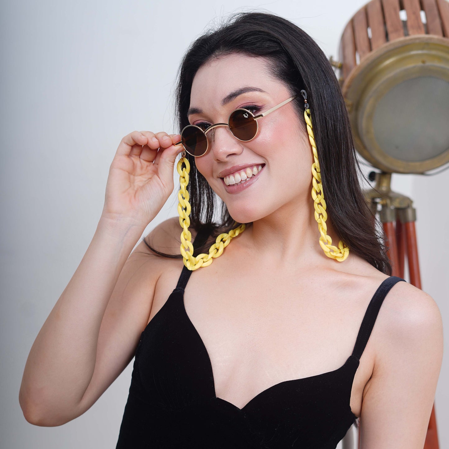 Small-sized sized charming, round, oval brown tinted shades lenses attached with a yellow funky chain-side pose