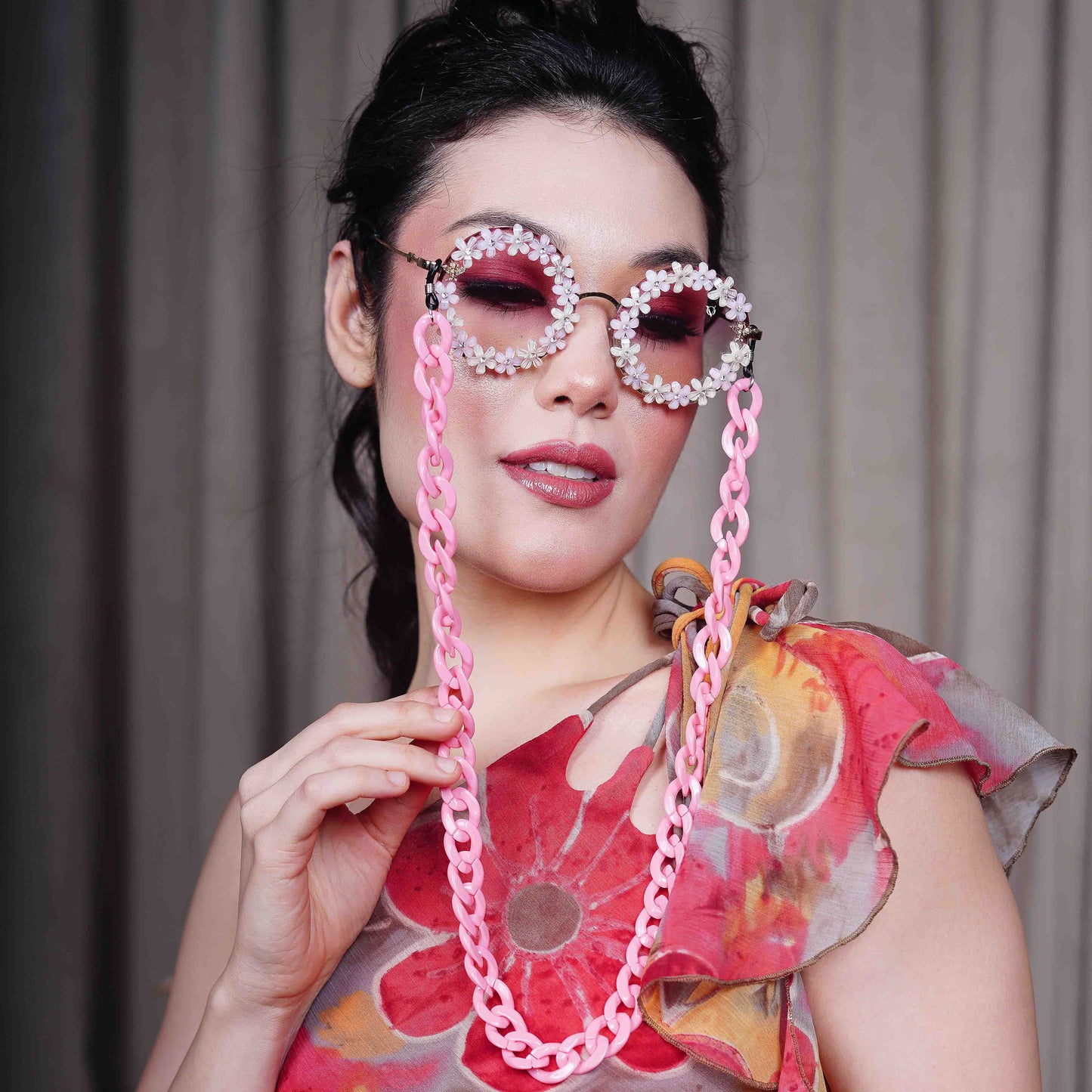 Elegant round sunglasses with floral crystal-studded finishing, adorned with a pink funky chain for a playful vibe-side angle pose
