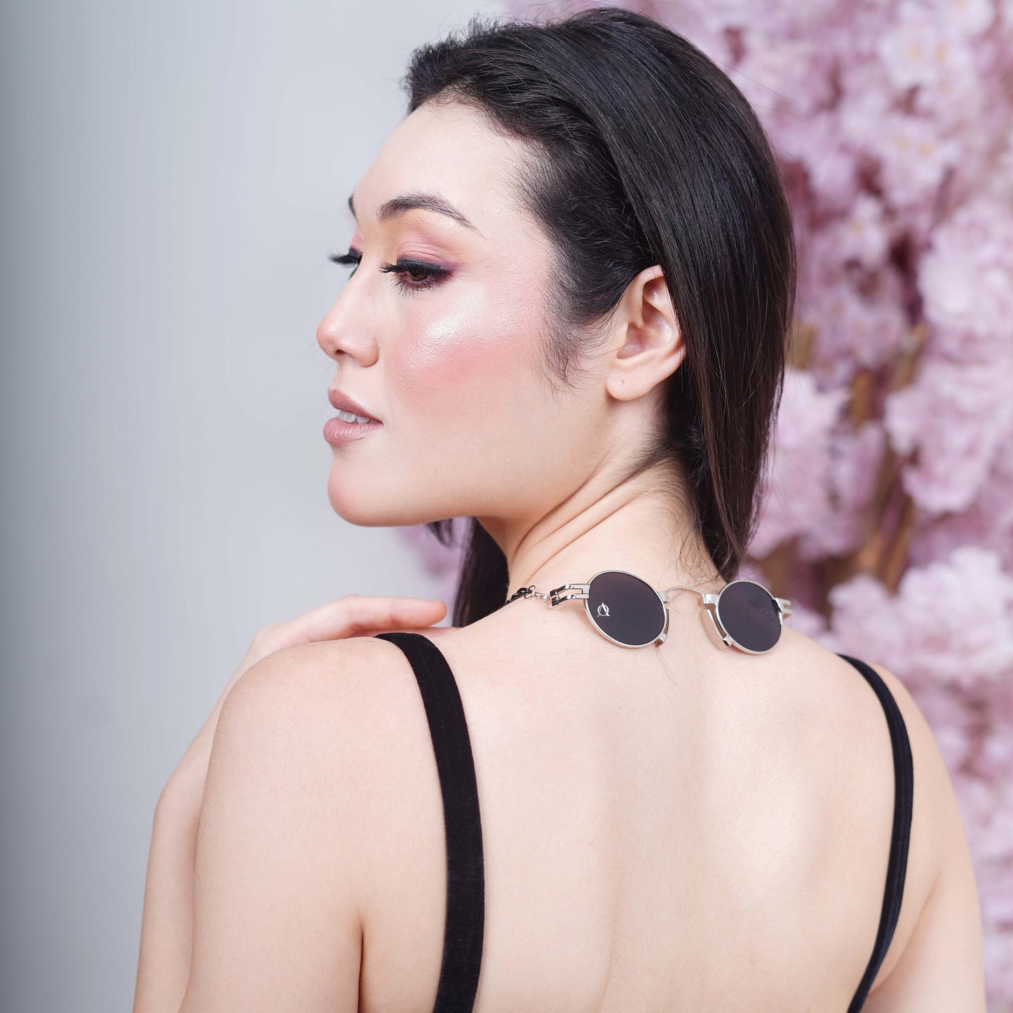 Elegant oval black tinted silver metal finished lenses adorned with a black chain and black charms attached with a silver metal holder-back pose