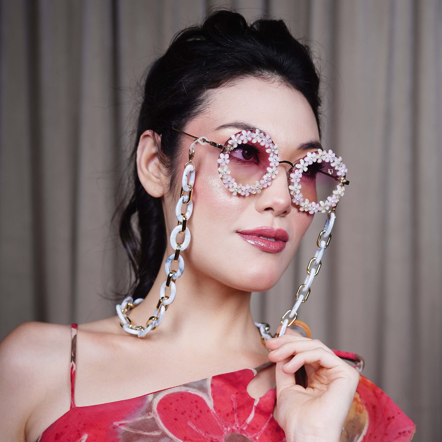 Elegant round sunglasses with floral crystal-studded finishing, adorned with a white funky chain for a playful vibe-side view