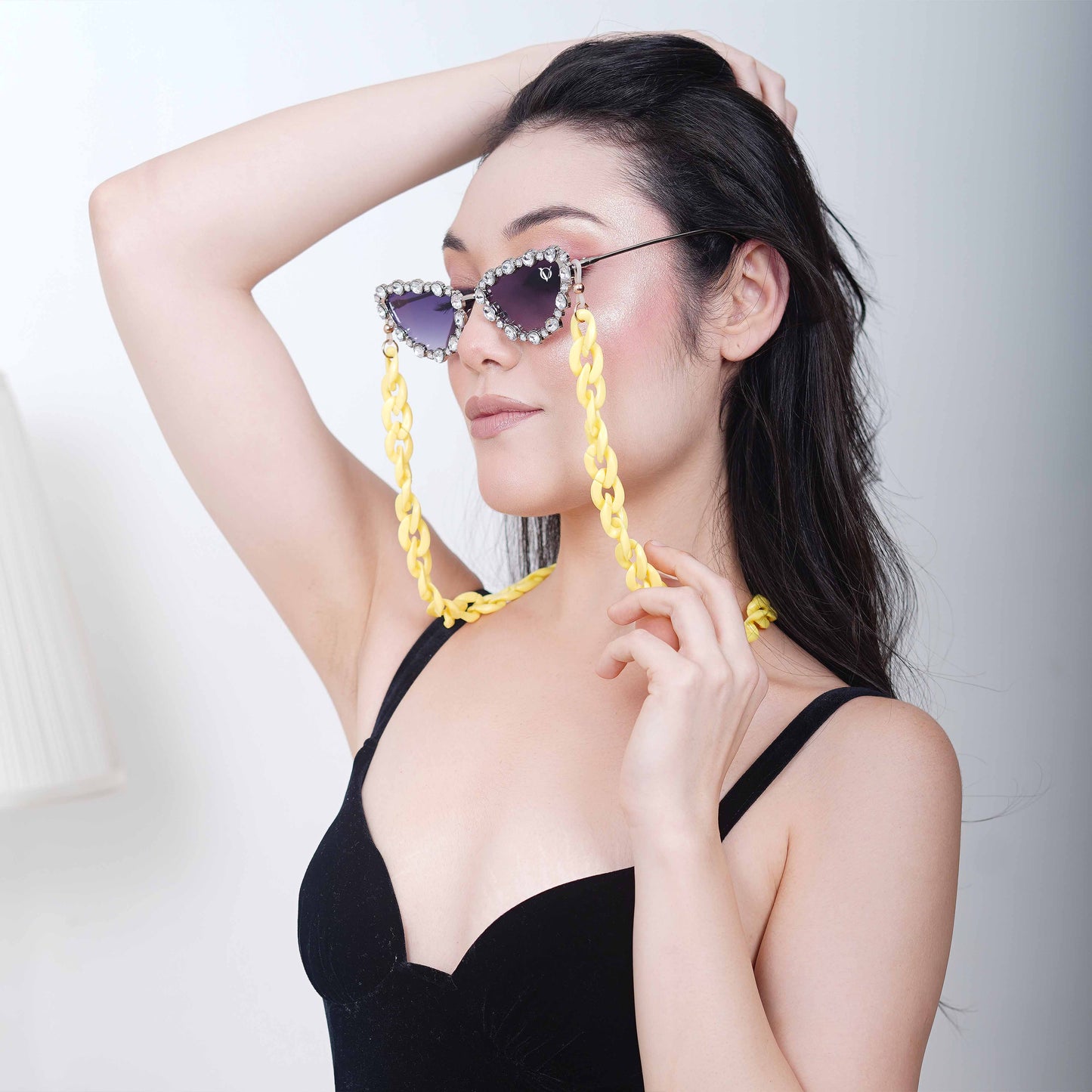 Glimmery oval crystal-studded cat-eye frames with blue gradient lenses attached with a yellow funky chain for trend lovers-side pose
