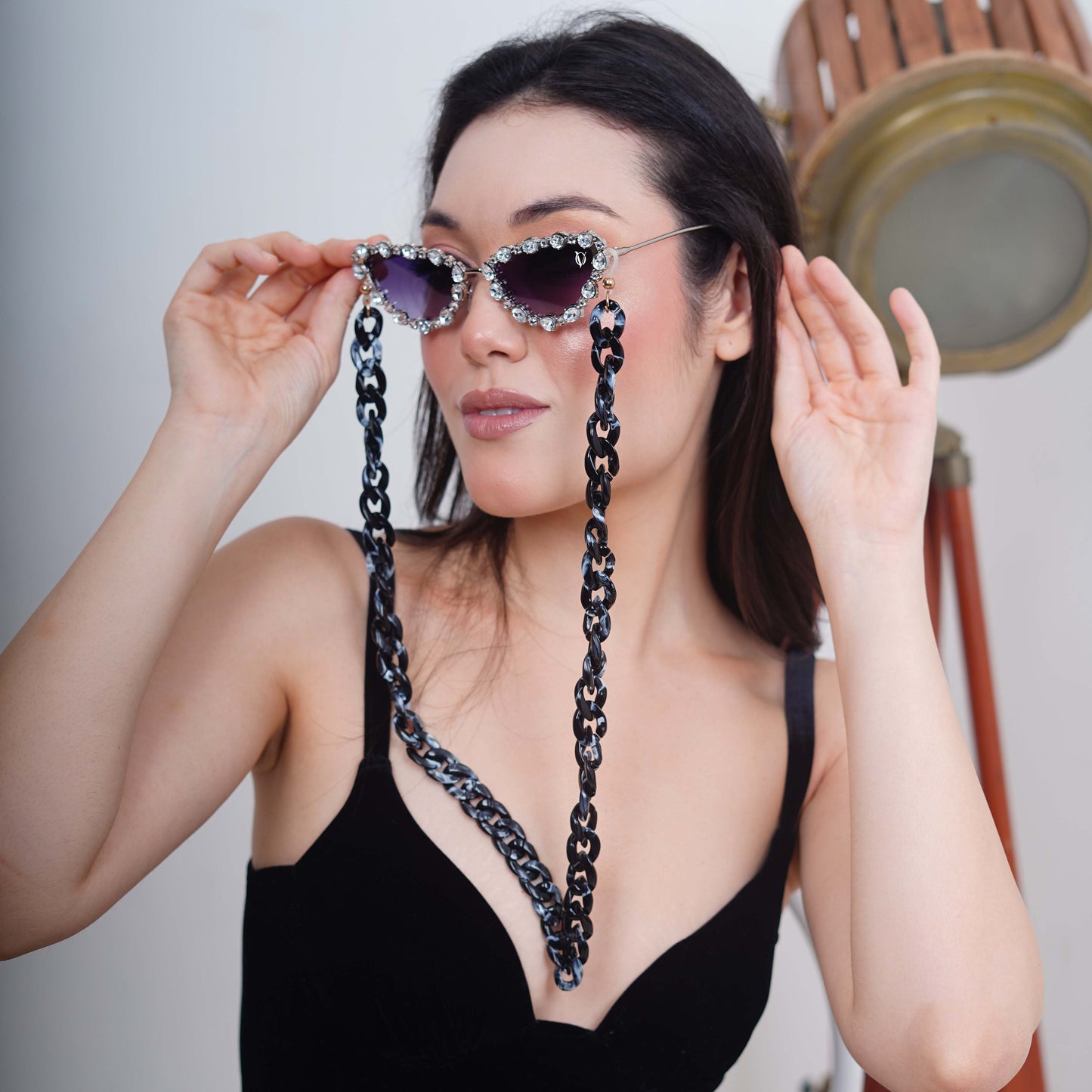 Glimmery oval crystal-studded cat-eye frames with purple gradient lenses attached with a blue-black gradient chain for fashion lovers-angle pose