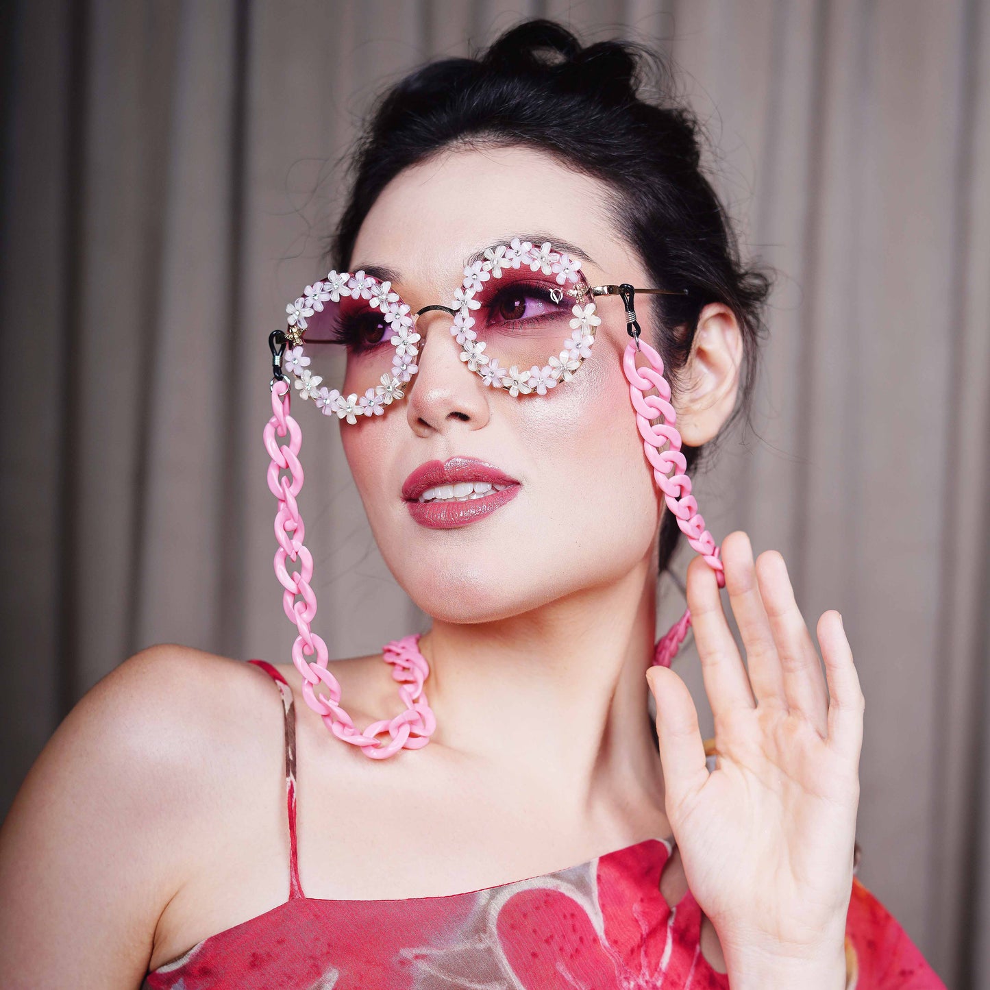 Elegant round sunglasses with floral crystal-studded finishing, adorned with a pink funky chain for a playful vibe-left angle pose