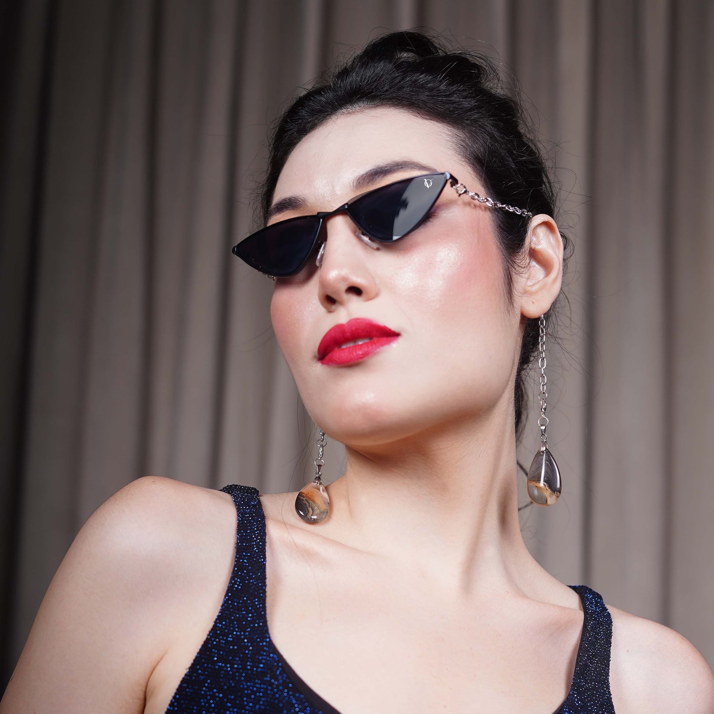 Bold, pointed black cat eye frames attached with a gold chain and adorned with gold-brown gradient clear charms-angle view