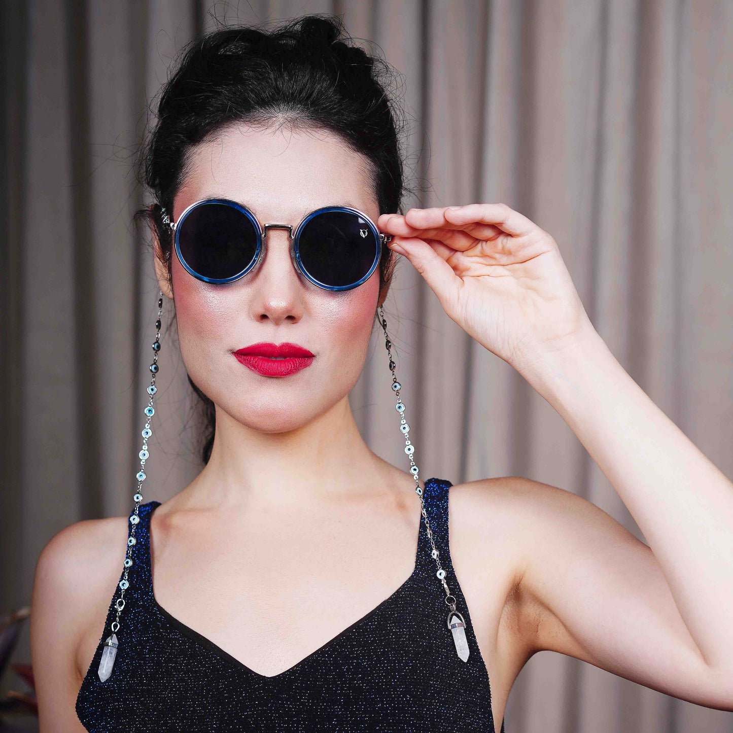 Trendy oversized blue round lenses adorned with a silver-tone evil eye chain and translucent white charm for a fashion statement-front angle pose