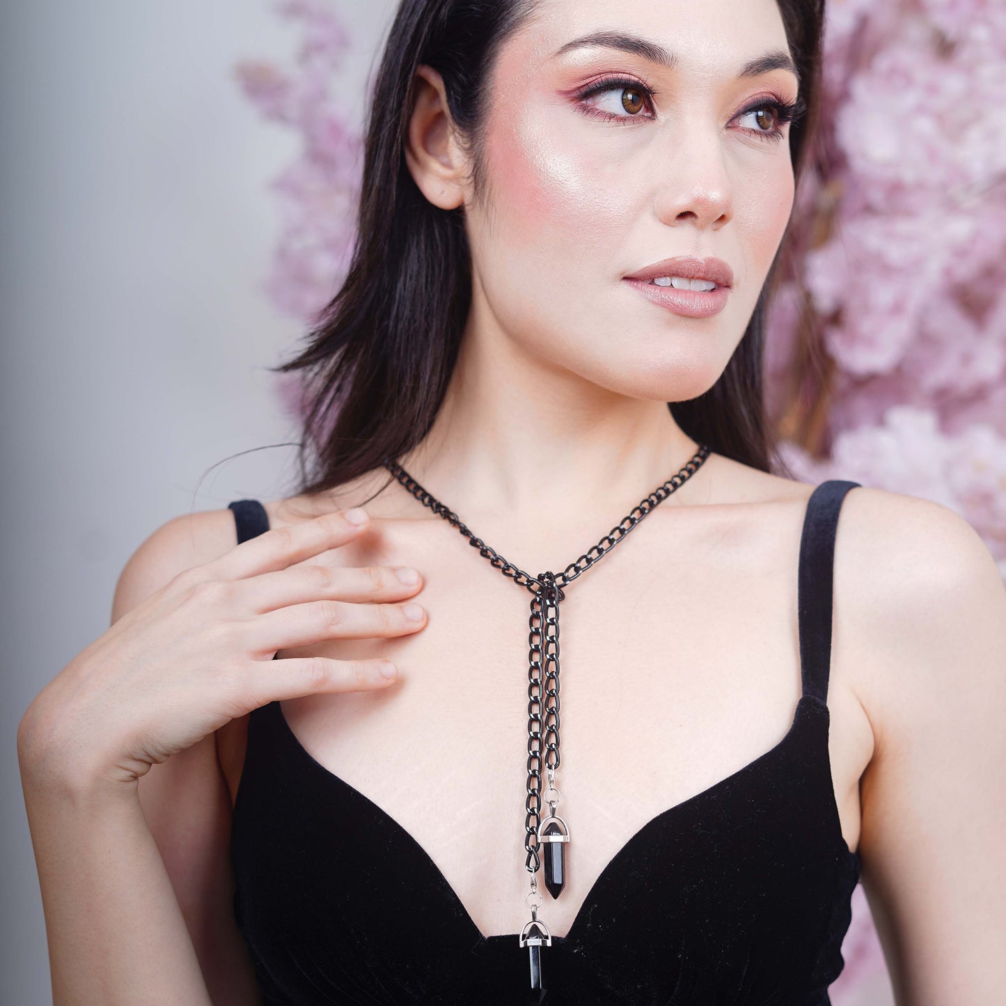 Elegant oval black tinted silver metal finished lenses adorned with a black chain and black charms attached with a silver metal holder-styling pose