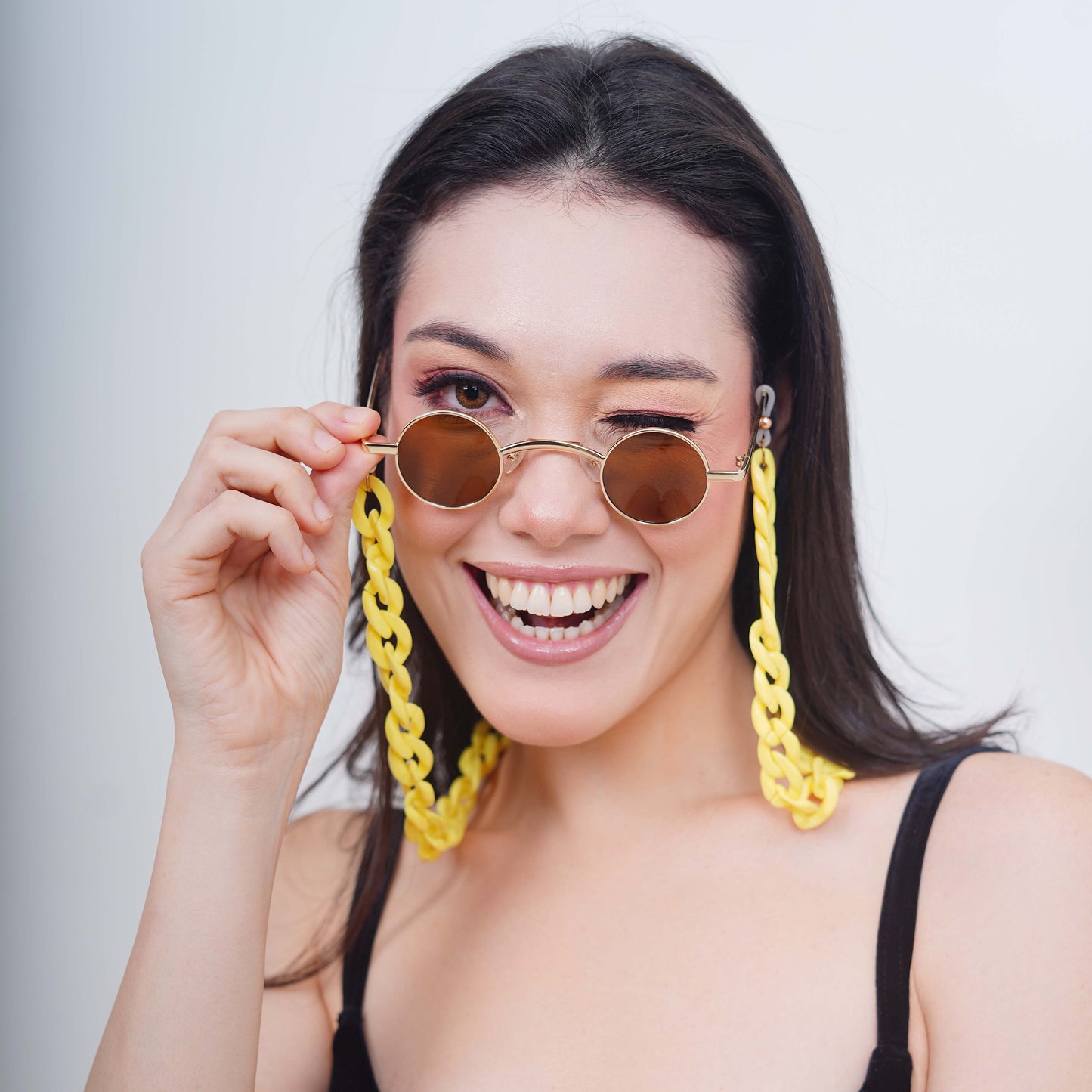 Small-sized sized charming, round, oval brown tinted shades lenses attached with a yellow funky chain-smiling pose