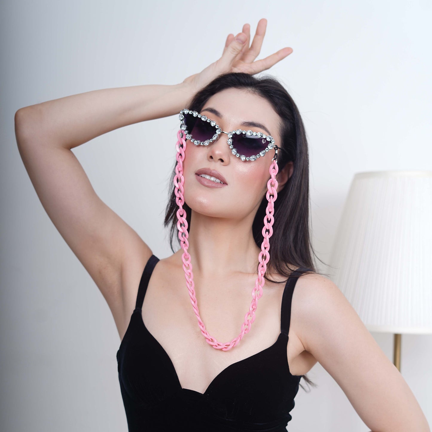 Glimmery oval crystal-studded cat-eye frames with blue gradient lenses attached with a pink funky chain for trend lovers-model style view