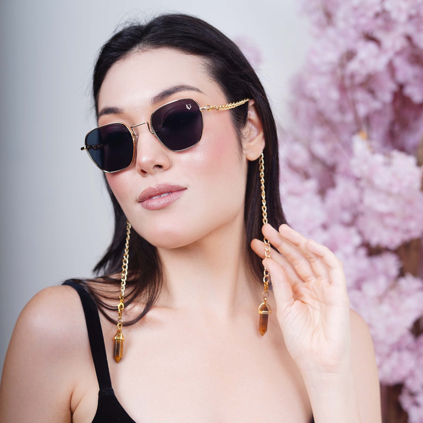 Black tinted large lenses with gold finishing attached with a golden chain with golden clear lenses finished with a gold metal holder-side styling pose