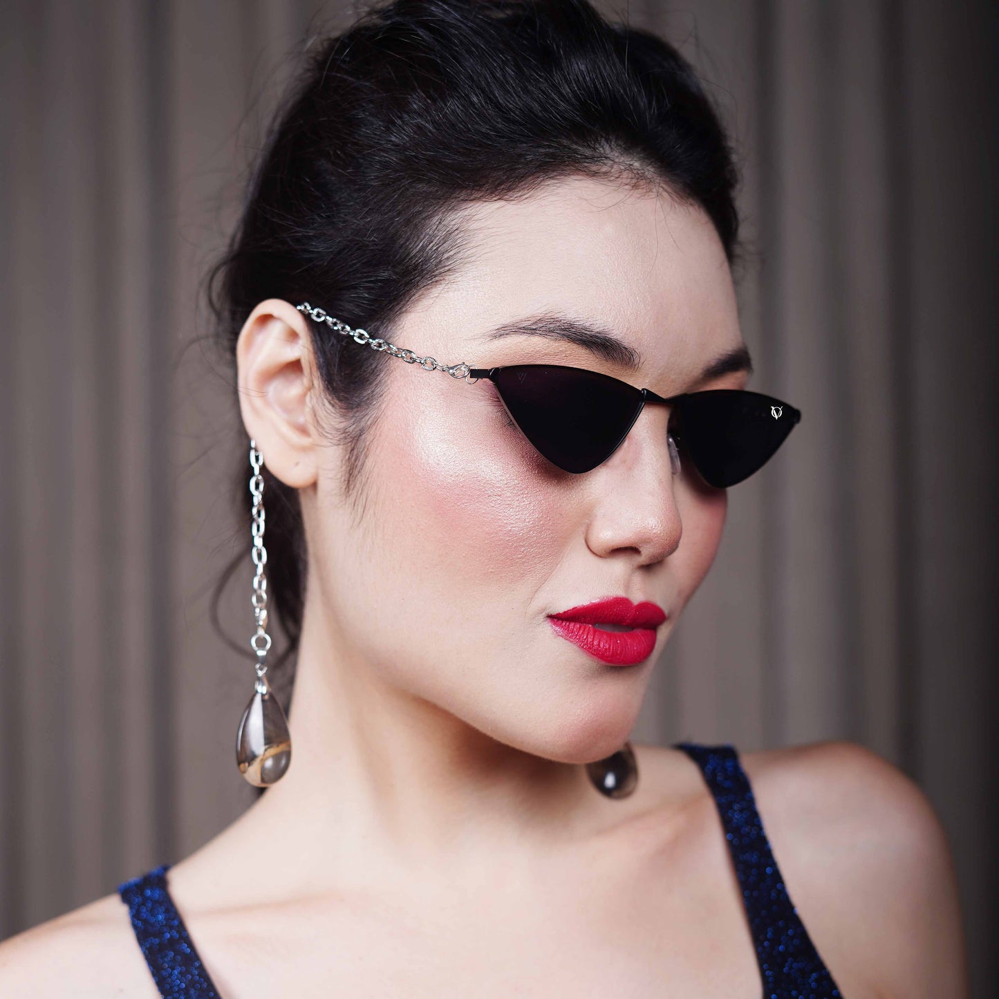 Bold, pointed black cat eye frames attached with a gold chain and adorned with gold-brown gradient clear charms-styling view
