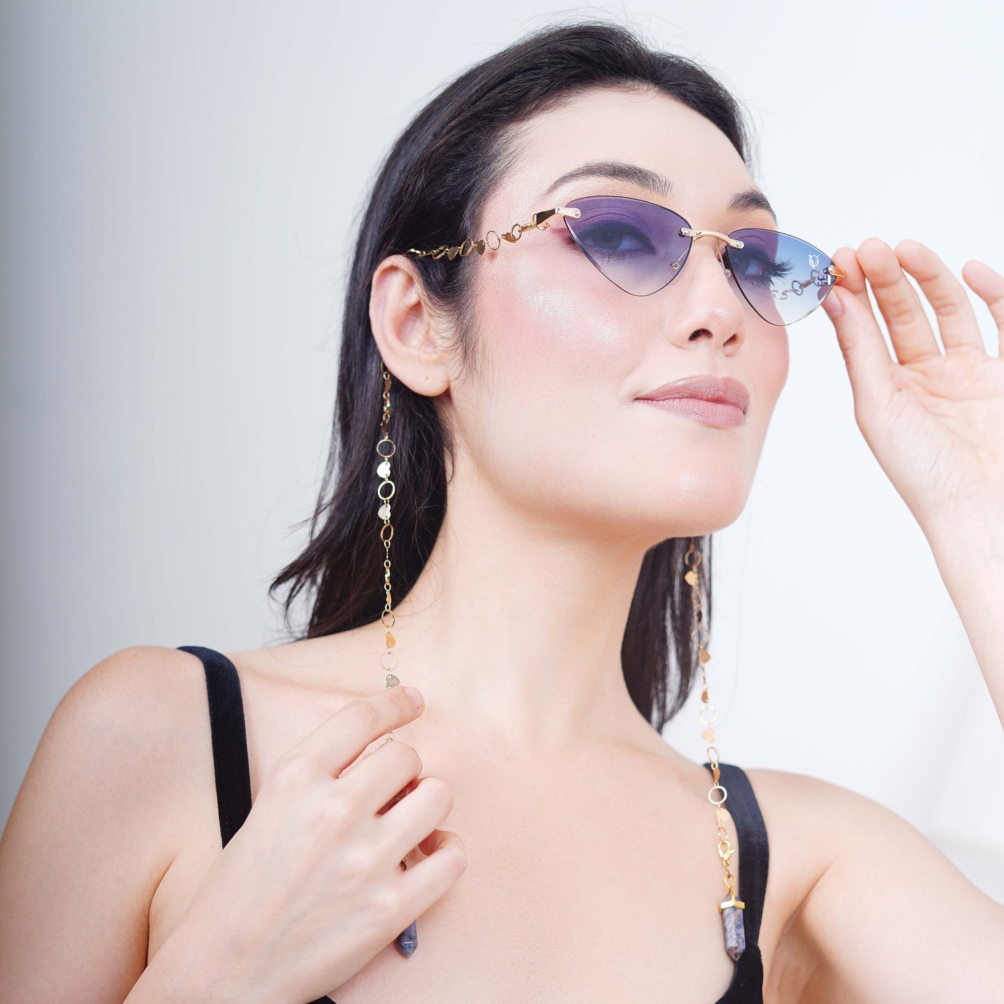 Authentic cat-eye frames with blue gradient-tinted lenses adorned with a gold-toned dual-linker chain of oval rings and leaf discs with vibrant blue charms-side pose