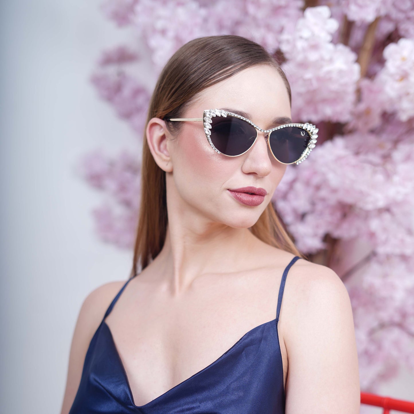 Woman wearing cat-eye sunglasses with dark lenses and a rhinestone-embellished frame.-angle view