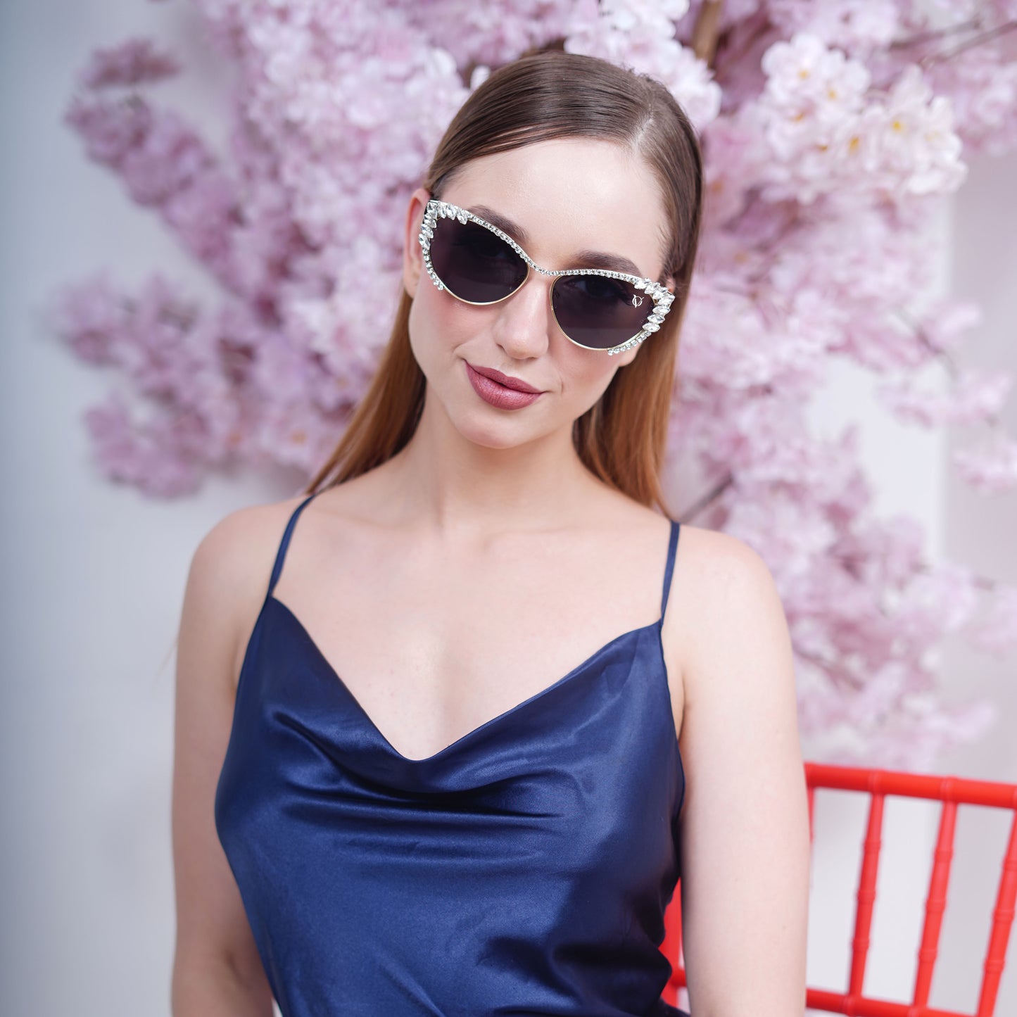 Woman wearing cat-eye sunglasses with dark lenses and a rhinestone-embellished frame-styling view