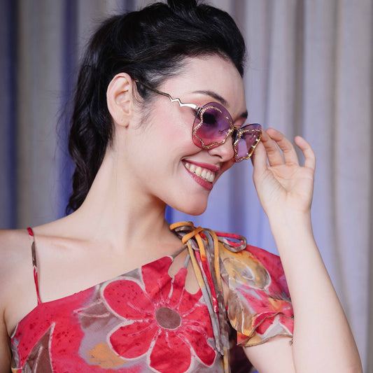 stylish heart-shaped sunglasses with purple-pink gradient lenses and a decorative golden frame-angle view