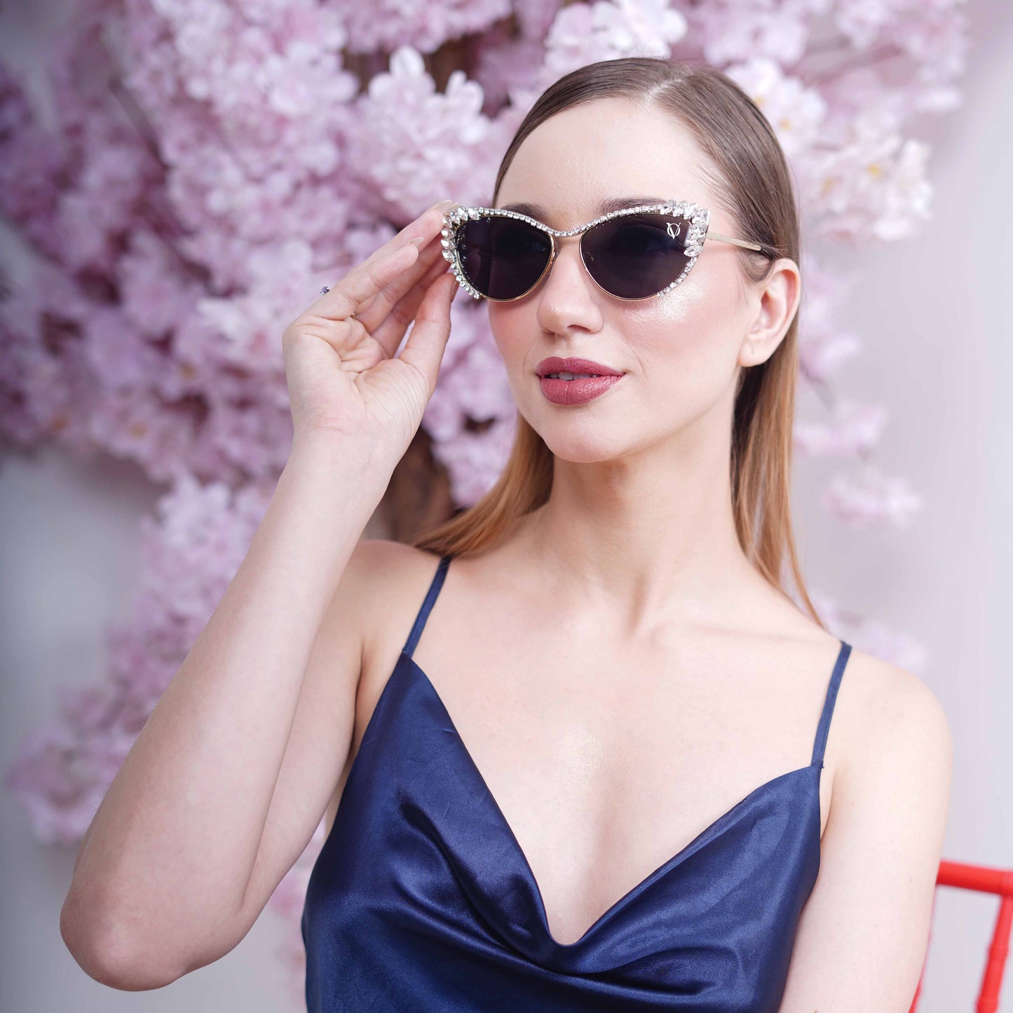 Woman wearing cat-eye sunglasses with dark lenses and a rhinestone-embellished frame-front view