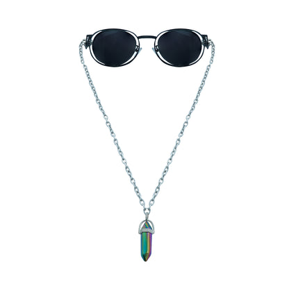 A pair of round, dark-lensed sunglasses with a silver frame is connected to a silver chain, which holds a pendant shaped holographic vibrant rainbow crystal-front view