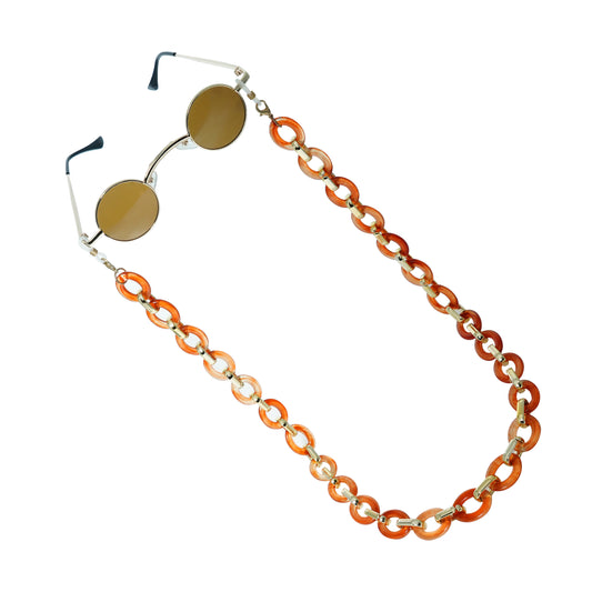 Small round brown tinted lenses with silver metal finishing attached with a large orange-white chain-tilted pose