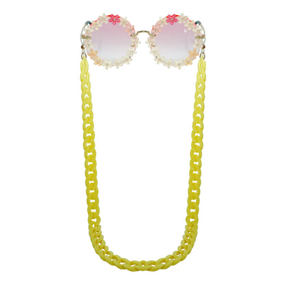 Sunglasses with gradient orange shade flower crystal-studded lenses attached to a bold chunky yellow chain-front view