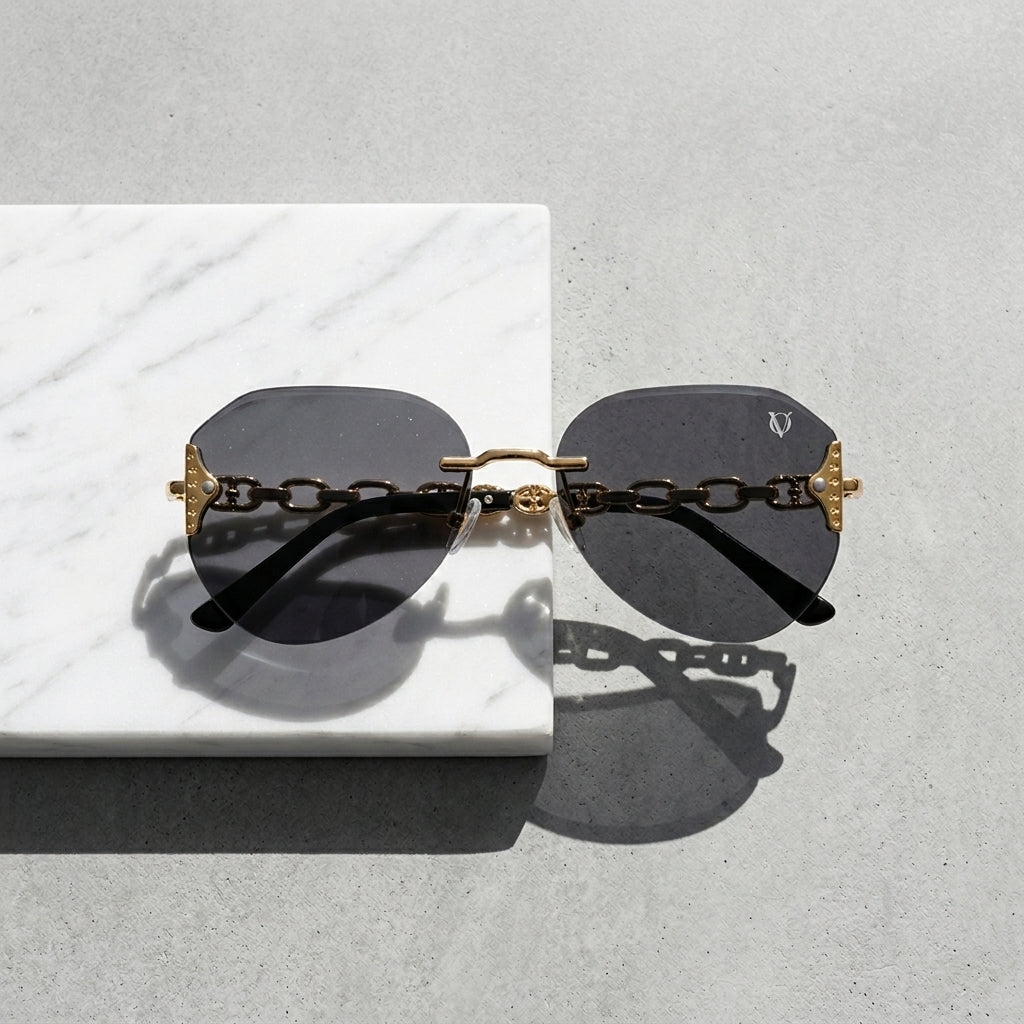 Sunglasses with gold chain design on a light gray surface