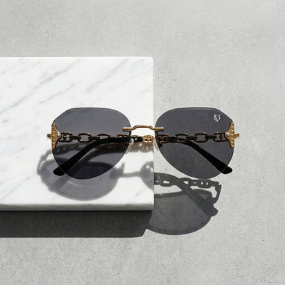 Sunglasses with gold chain design on a light gray surface