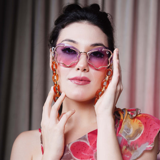 Shimmery red-purple gradient lens with gold glittery boundary attached with orange oval rings chain with gold linker-front view