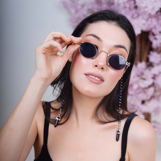 Elegant oval black tinted silver metal finished lenses adorned with a black chain and black charms attached with a silver metal holder-angle pose