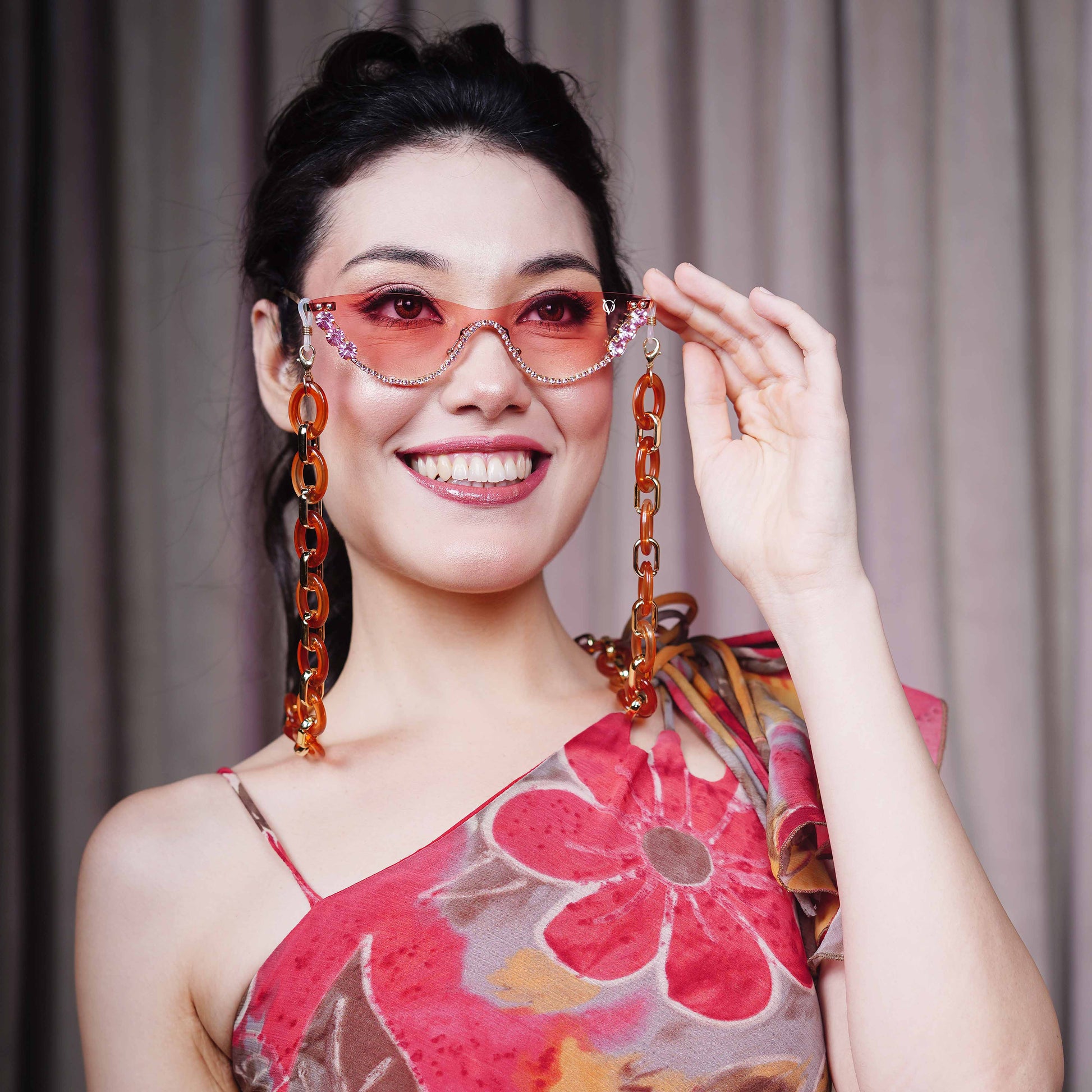 stylish pink sunglasses with gemstone frame and long orange chain attachments-front view