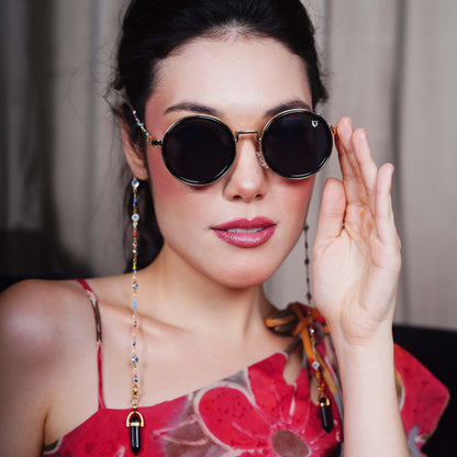 Large oversized dark-tinted golden polished lenses adorned with a multicolored bead chain attached with black charms finished with a gold metal holder-front pose