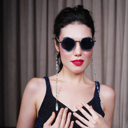 Trendy oversized blue round lenses adorned with a silver-tone evil eye chain and translucent white charm for a fashion statement-styling pose   

