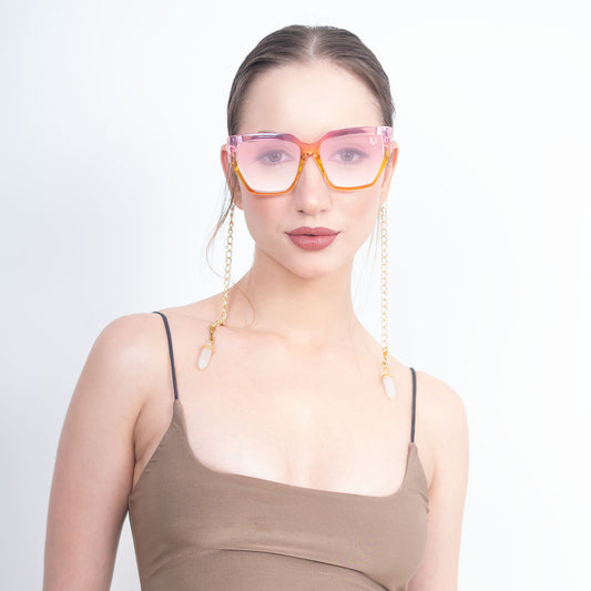 Trendy oversized orange-pink gradient large orange colored sunglasses with a golden chain and translucent white charms-front view