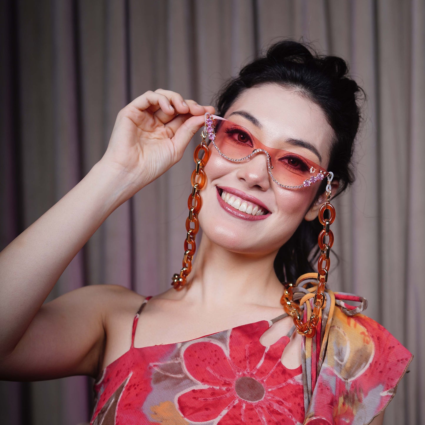 stylish pink sunglasses with gemstone frame and long orange chain attachments-smiling view