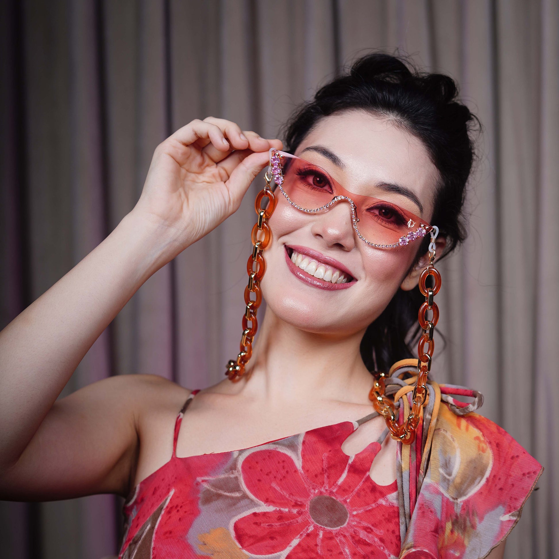 stylish pink sunglasses with gemstone frame and long orange chain attachments-smiling view