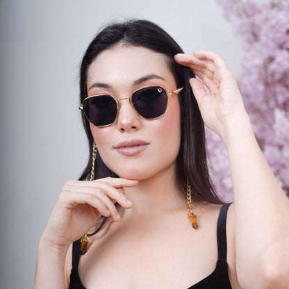 Black tinted large lenses with gold finishing attached with a golden chain with golden clear lenses finished with a gold metal holder-styling pose