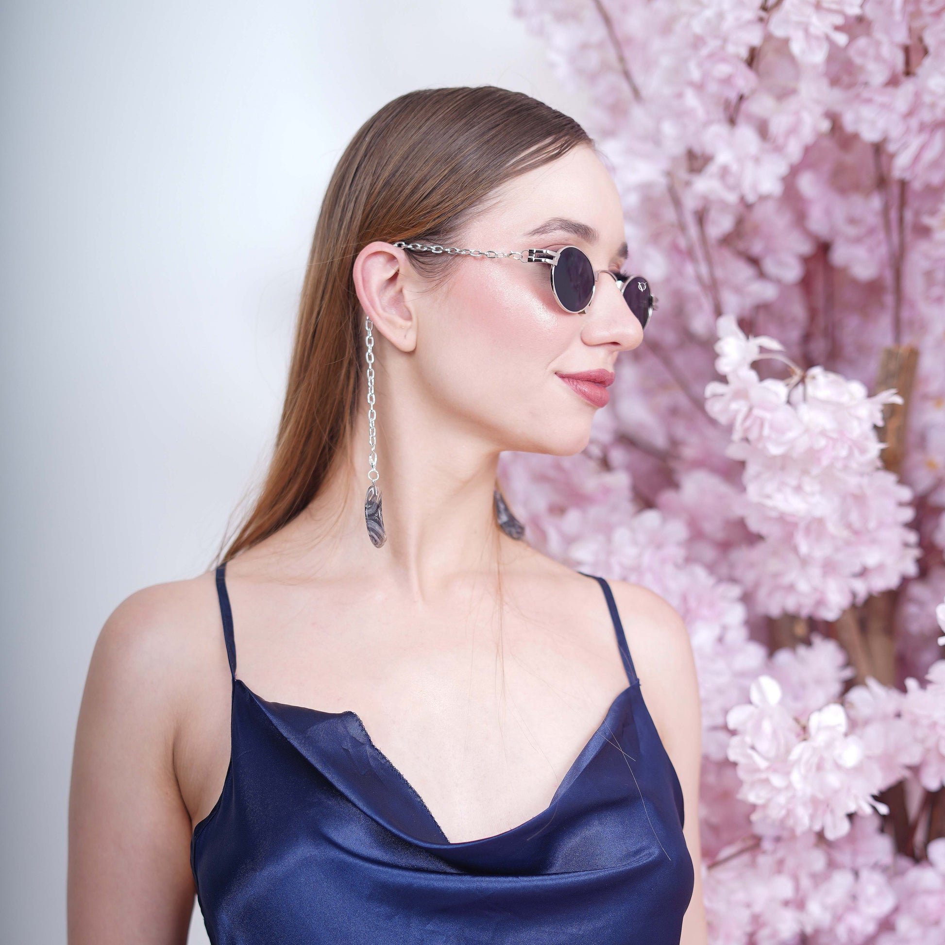 Charming oval-shaped frames with blue-tinted silver finished lenses attached with a silver chain and adorned with crescent-shaped bluish-green gradient charms-side view