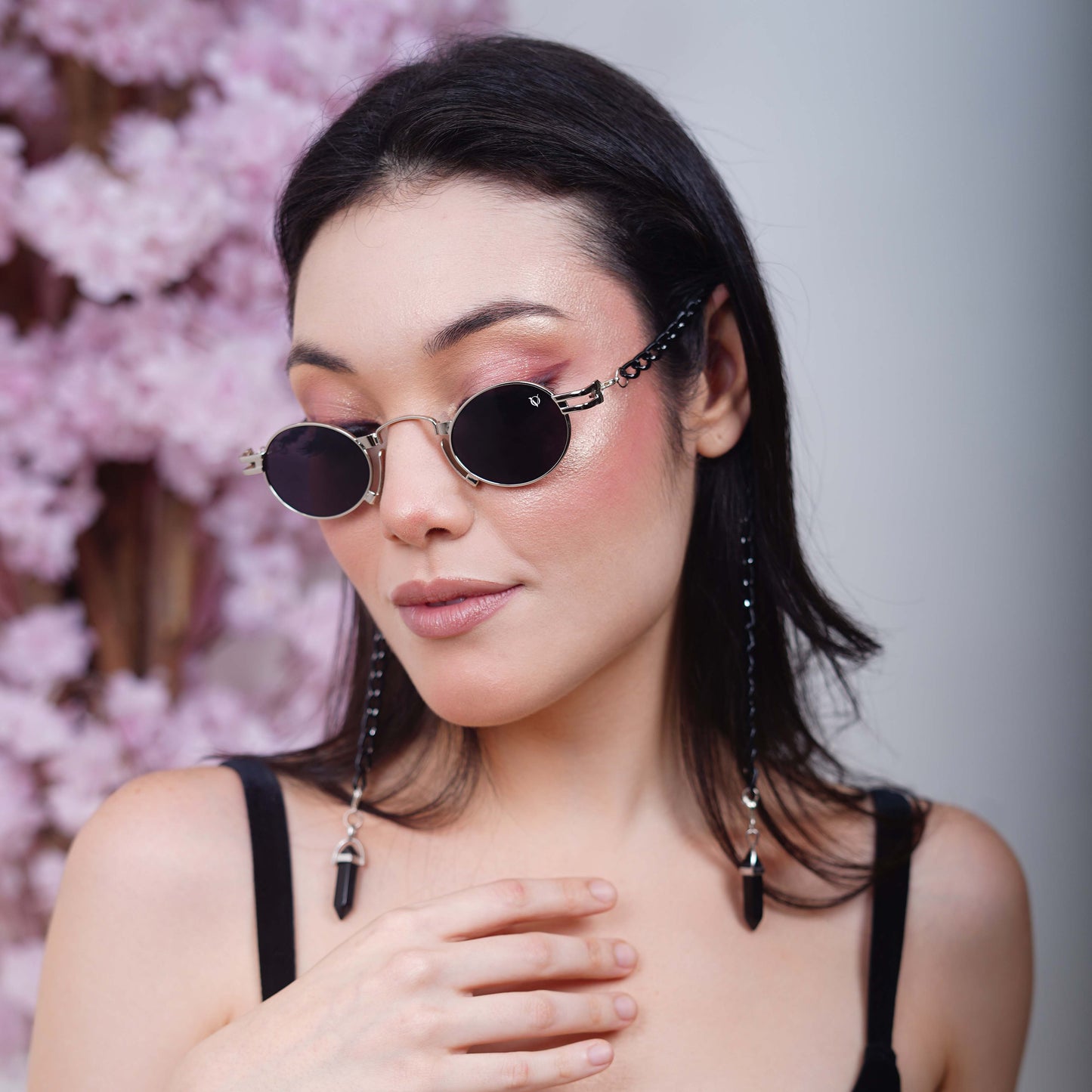 Elegant oval black tinted silver metal finished lenses adorned with a black chain and black charms attached with a silver metal holder- downfacing pose