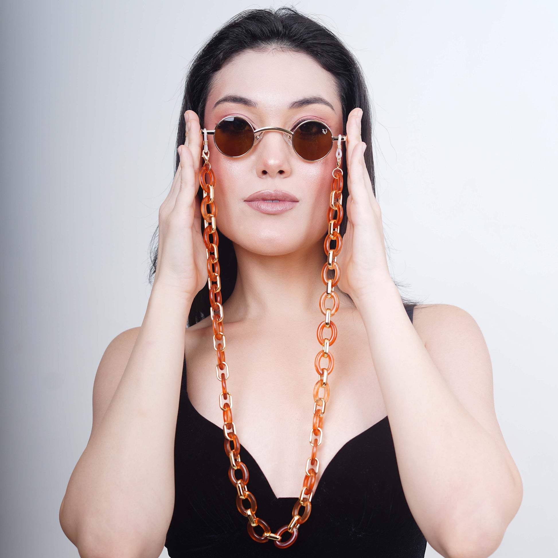 Luxurious brown tinted round oval lenses attached with a large funky orange chain linked with a gold linker.