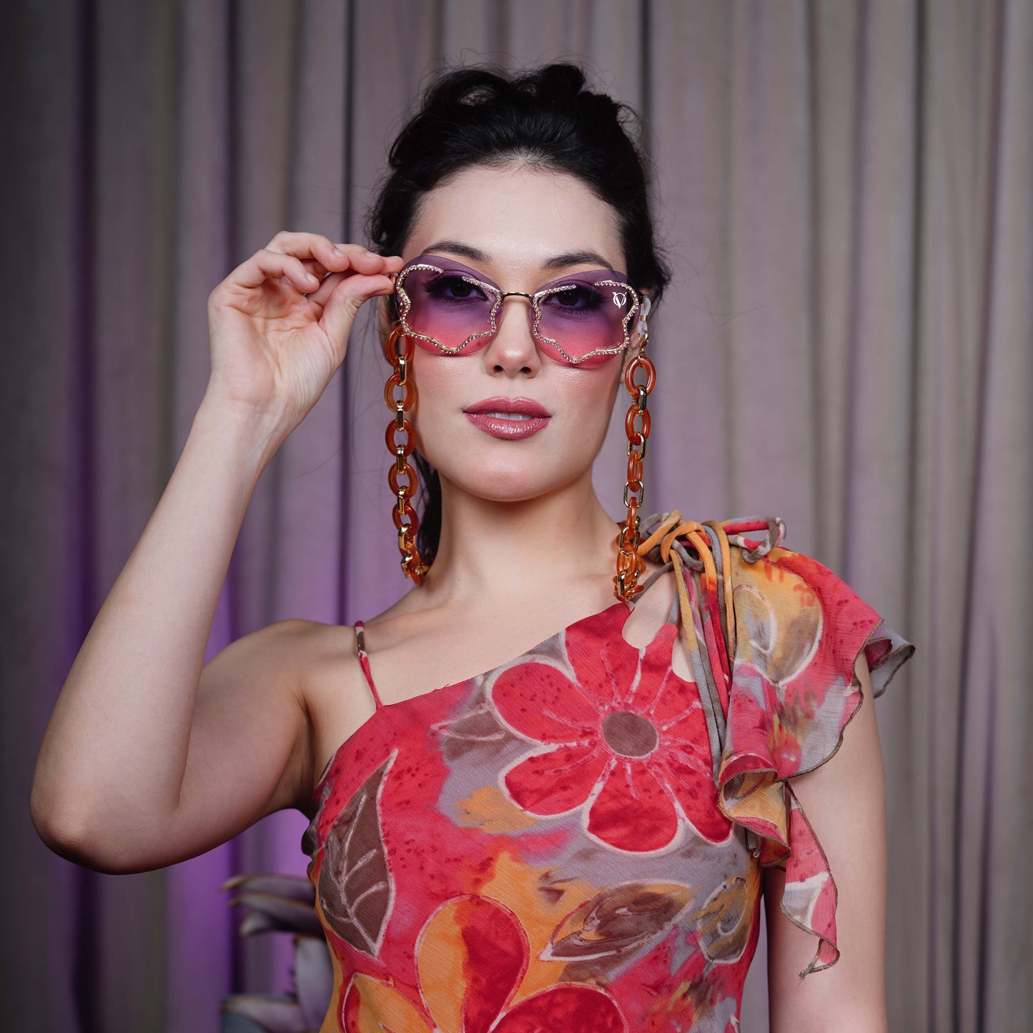 Shimmery red-purple gradient lens with gold glittery boundary attached with orange oval rings chain with gold linker-styling view