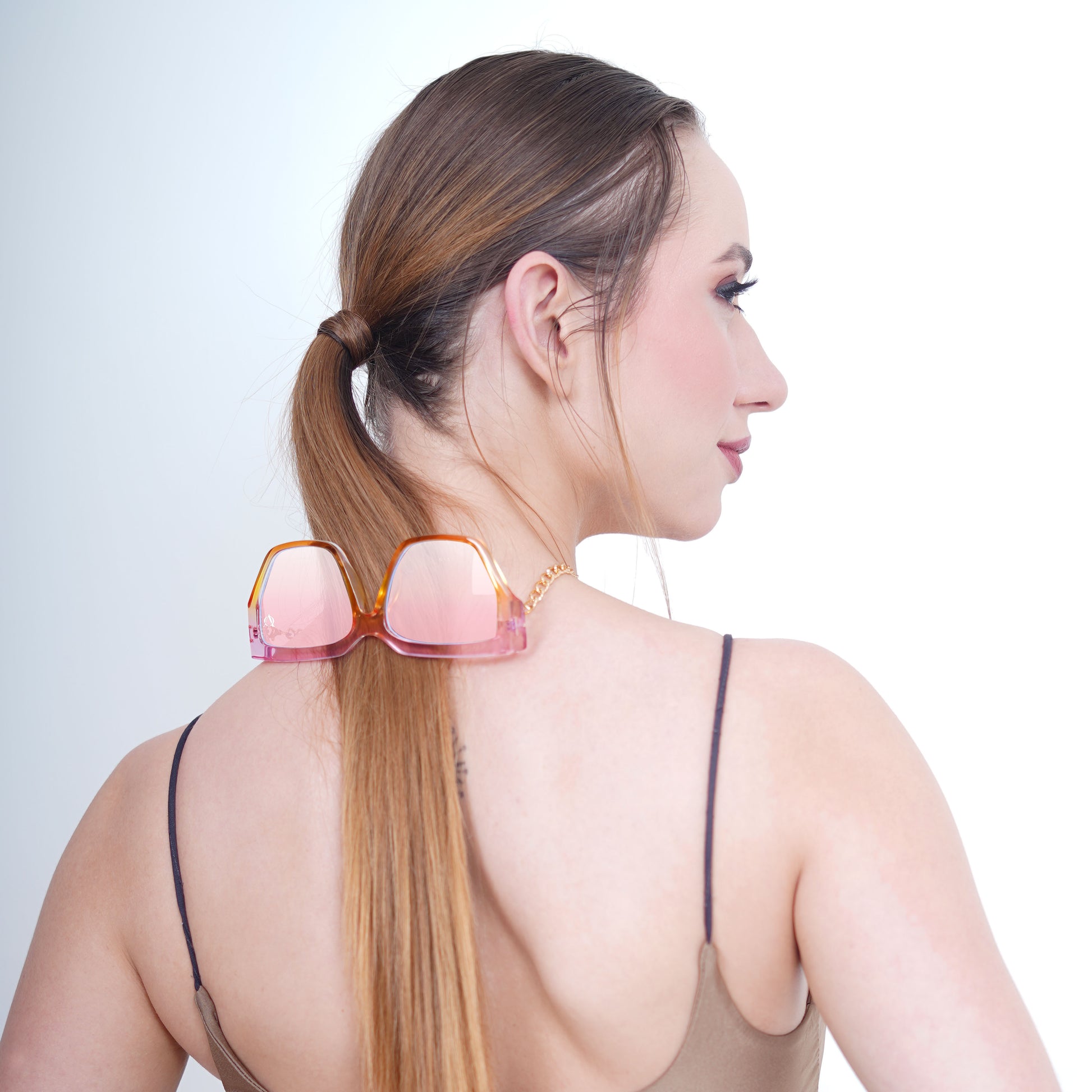 Trendy oversized orange-pink gradient large orange colored sunglasses with a golden chain and translucent white charms-back view