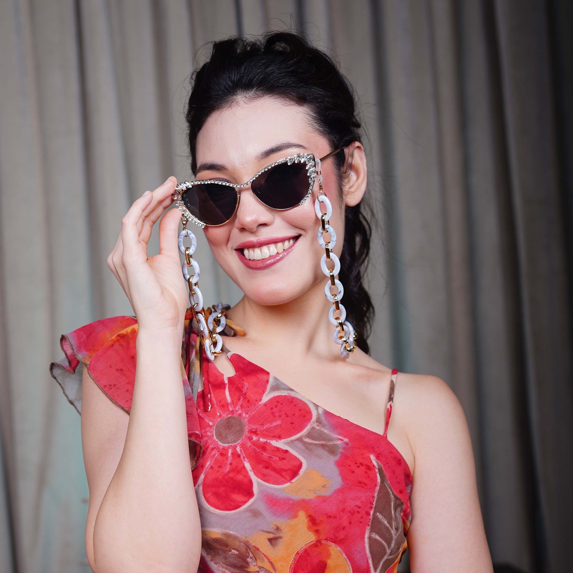Best crystal-studded cat-eye frames sunglasses with a white chain linked with a gold linker for women's to go to a party-sunglass holding pose 