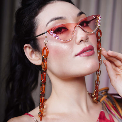 stylish pink sunglasses with gemstone frame and long orange chain attachments-side view