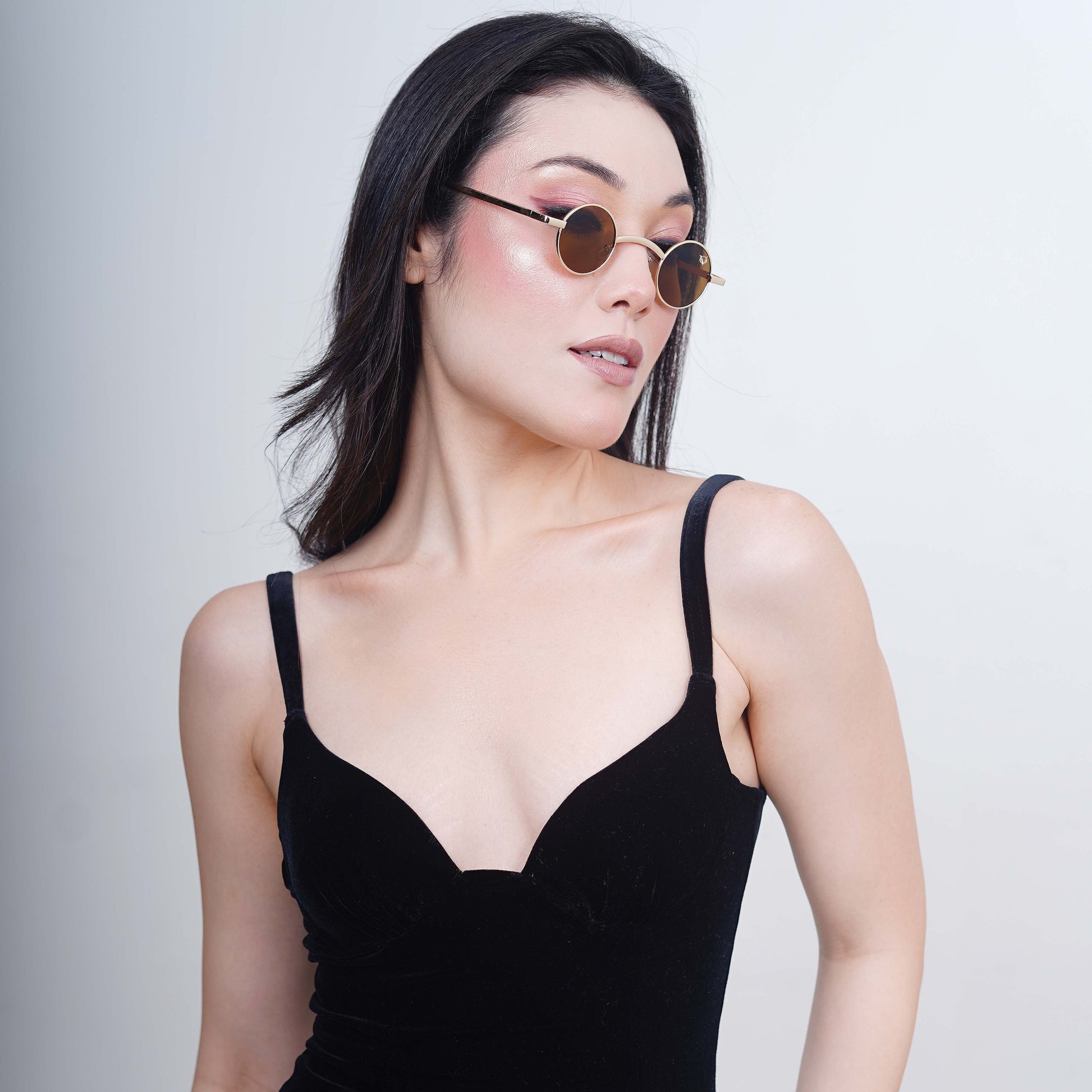 Round sunglasses with golden metallic frame and brown tinted lenses- side angle view